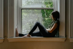 افسردگی در مهاجرت؛ زنی تنها و متفکر نشسته کنار پنجره